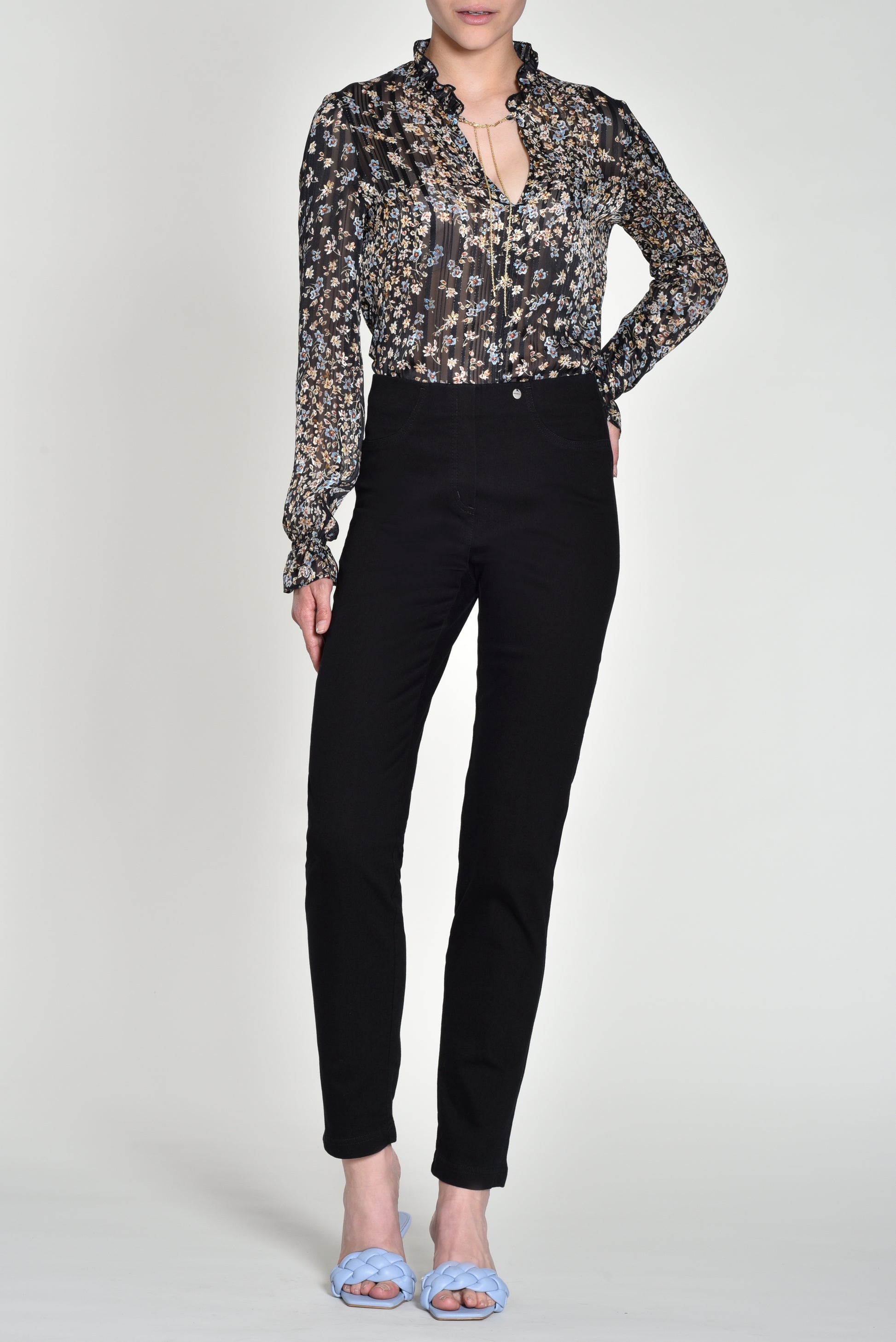 Person wearing a floral blouse and black pants on a white background
