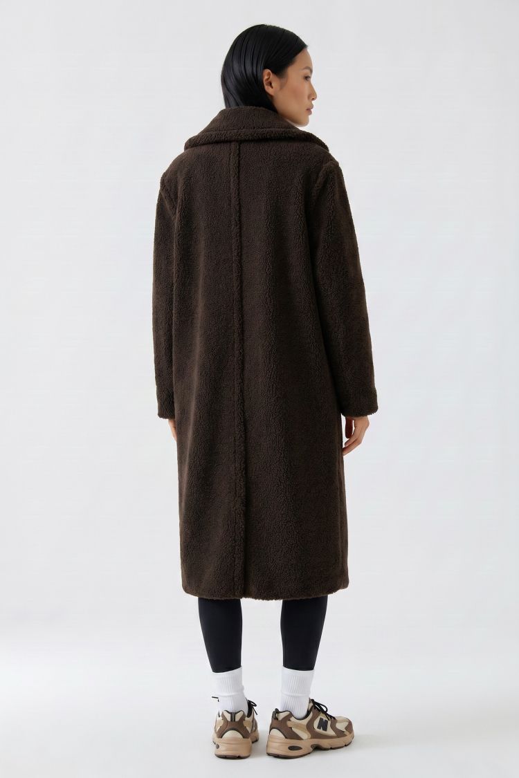 Person wearing a long brown coat on a white background
