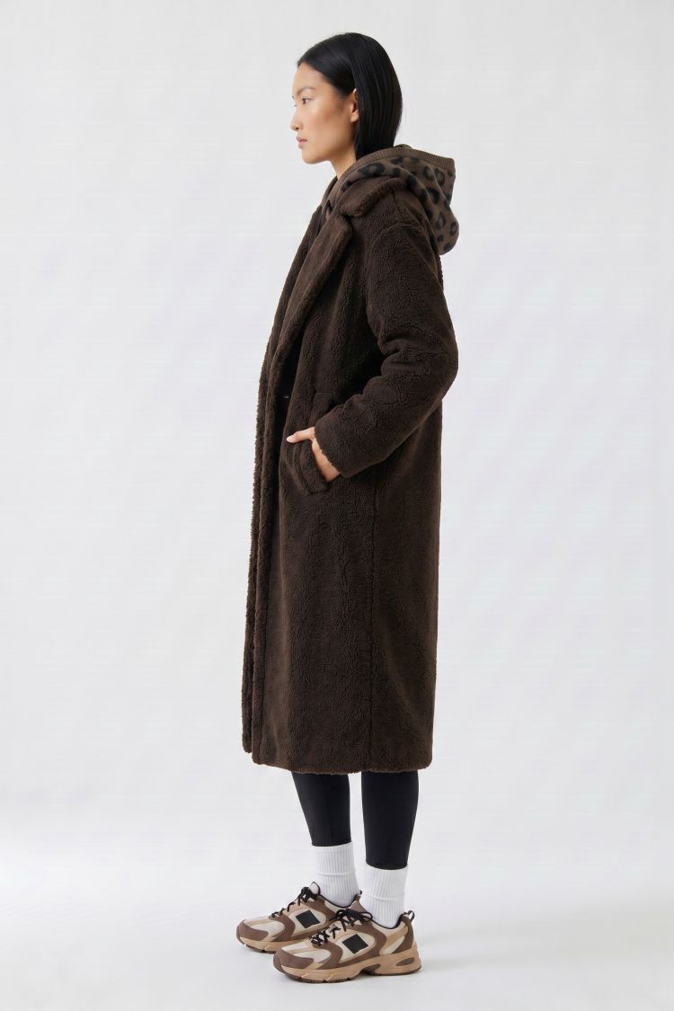 Person wearing a brown coat with a hood on a white background