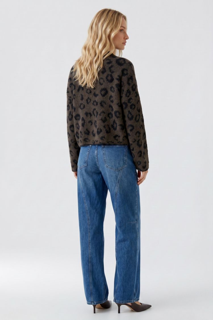 Woman wearing a leopard print sweater and blue jeans on a white background