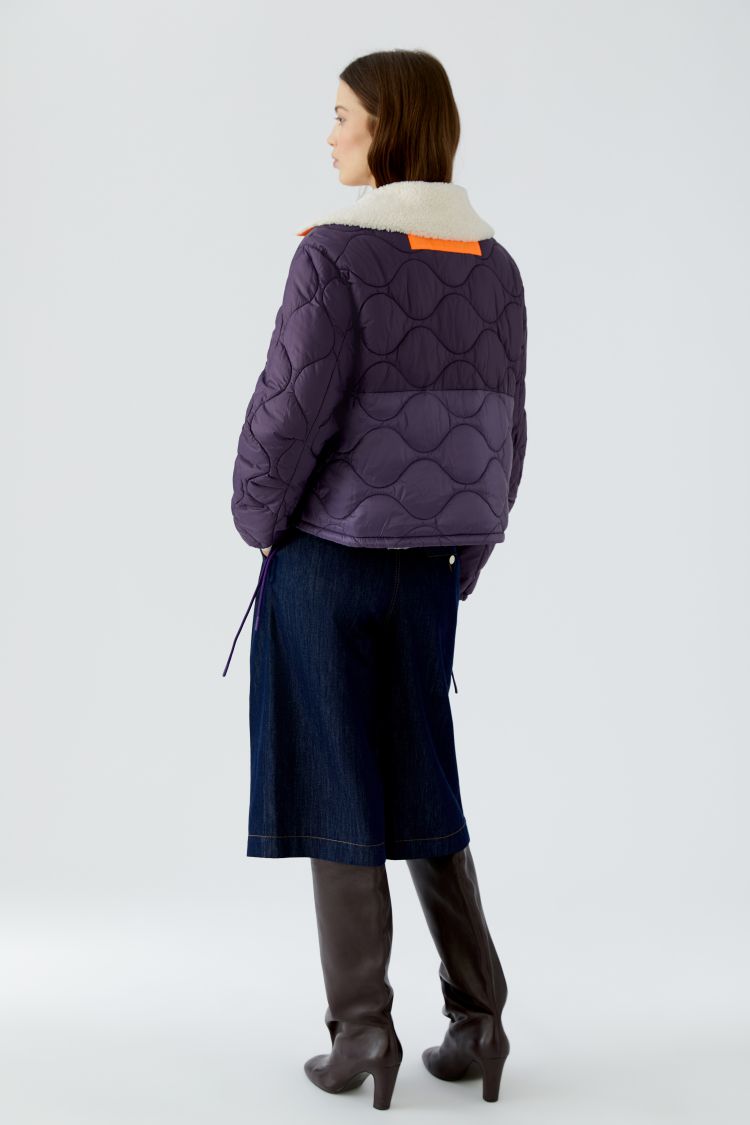 Person wearing a quilted jacket with a white background