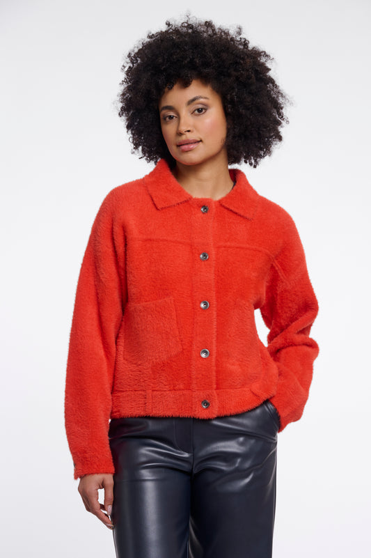Person wearing a red jacket with a plain background
