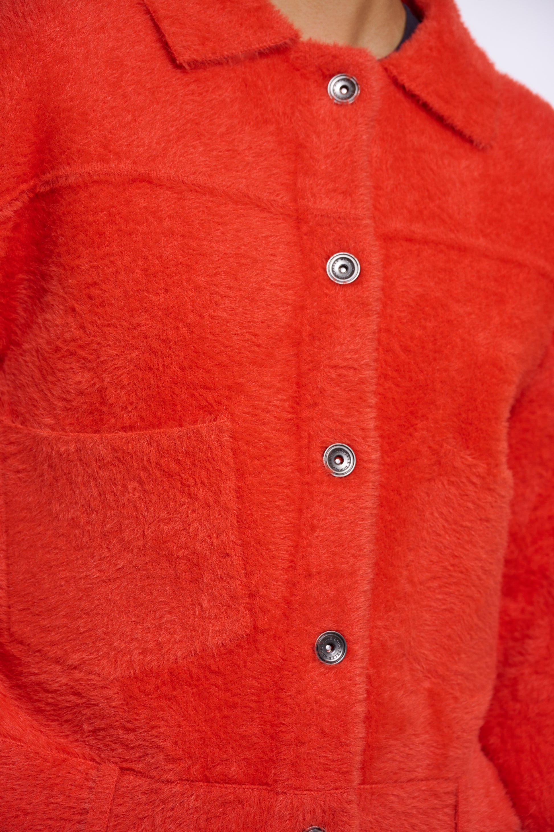 Close-up of a red textured jacket with buttons on a white background