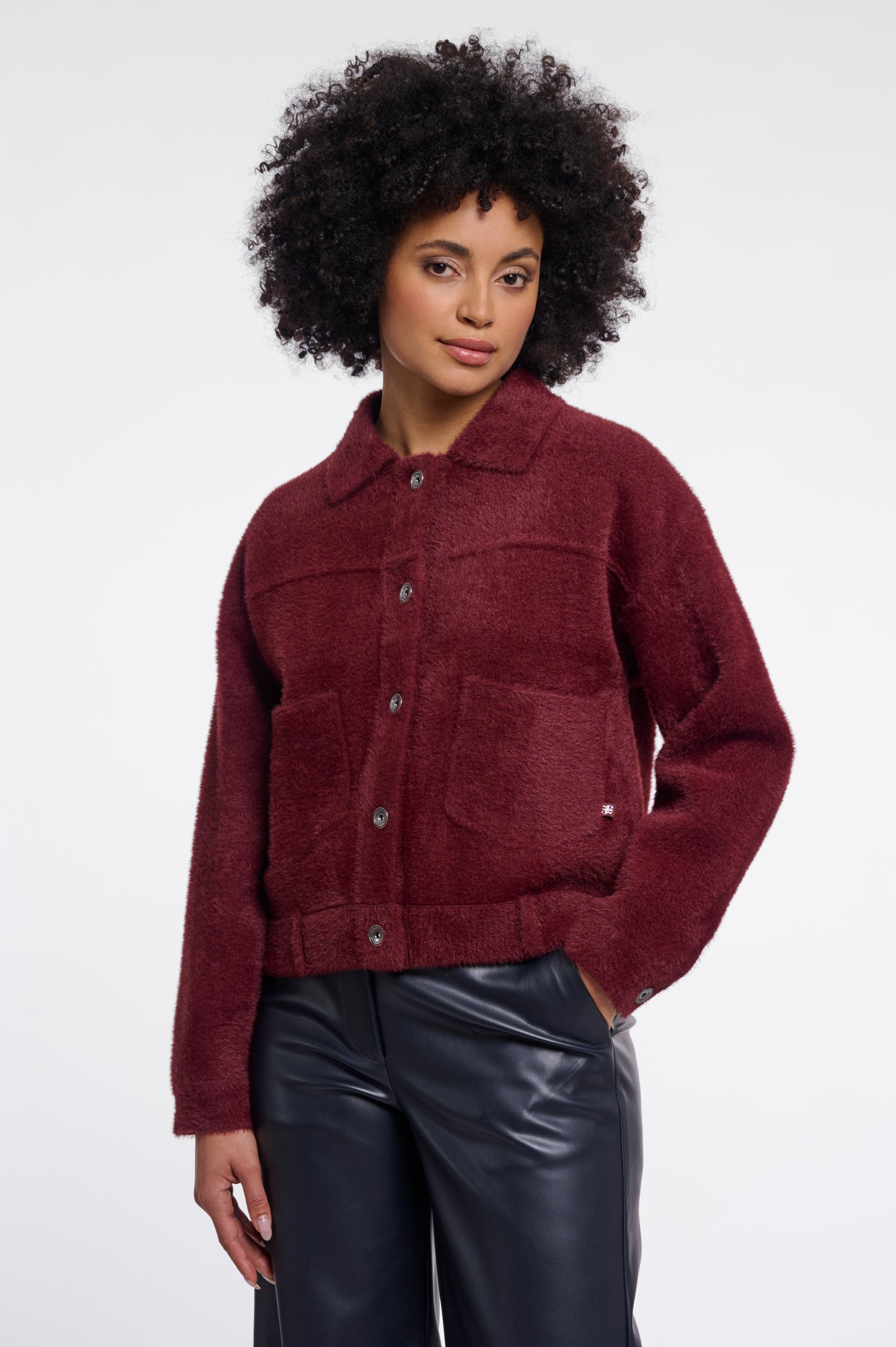 Woman wearing a burgundy jacket with a plain background