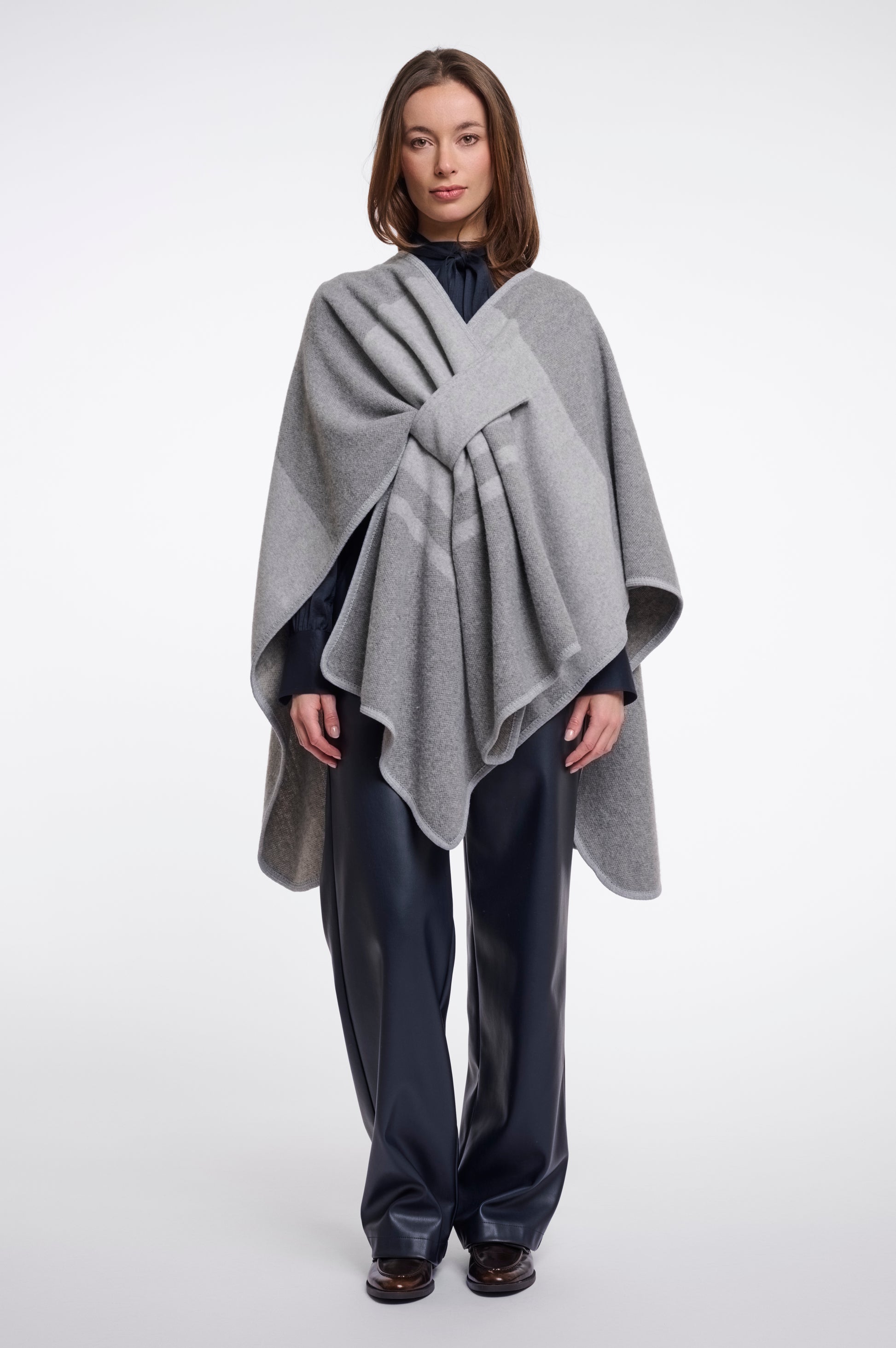 Woman wearing a gray poncho over a dark outfit on a white background