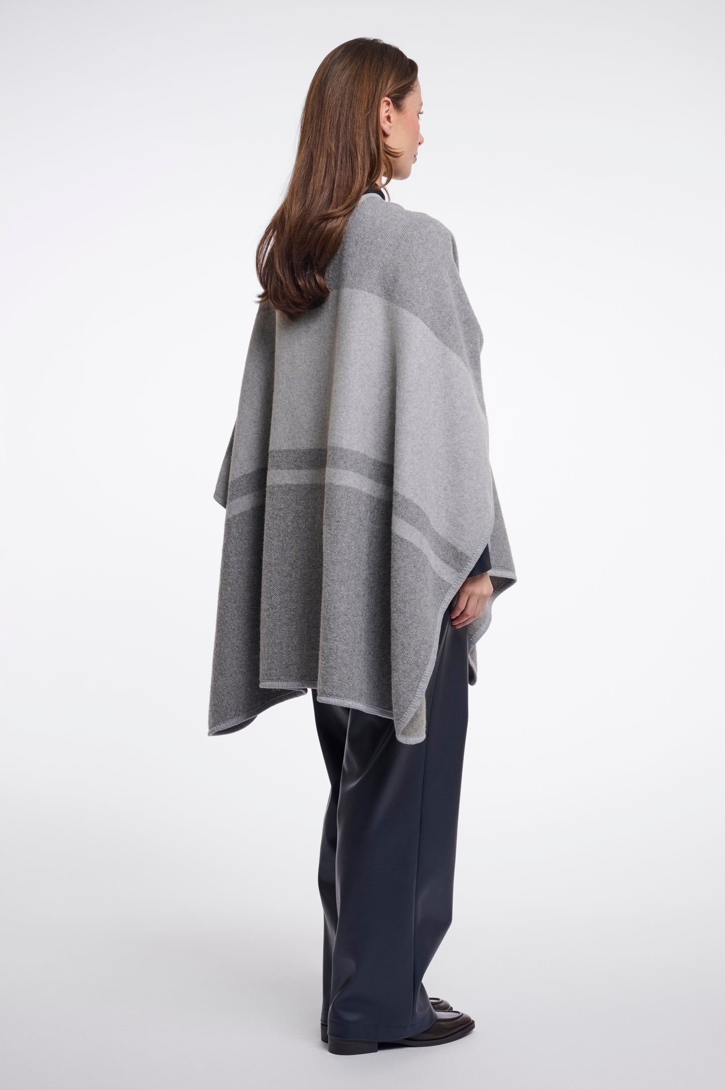 Woman wearing a gray and white striped poncho on a white background