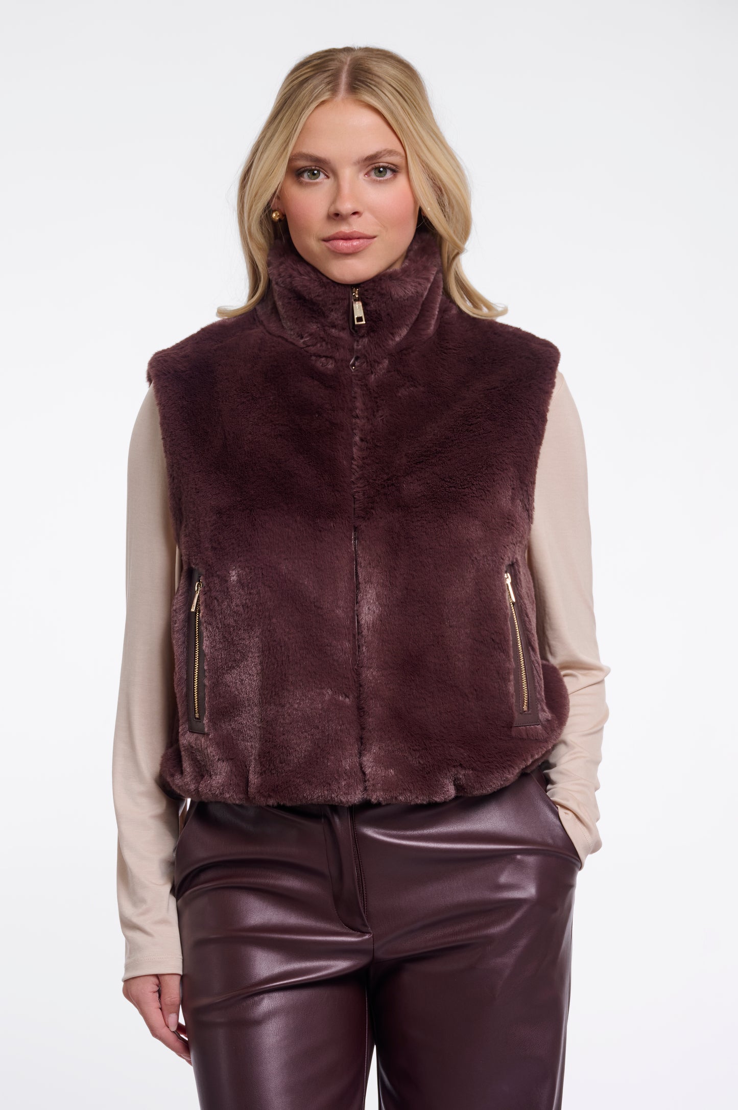 Woman wearing a brown fur vest and leather pants on a white background