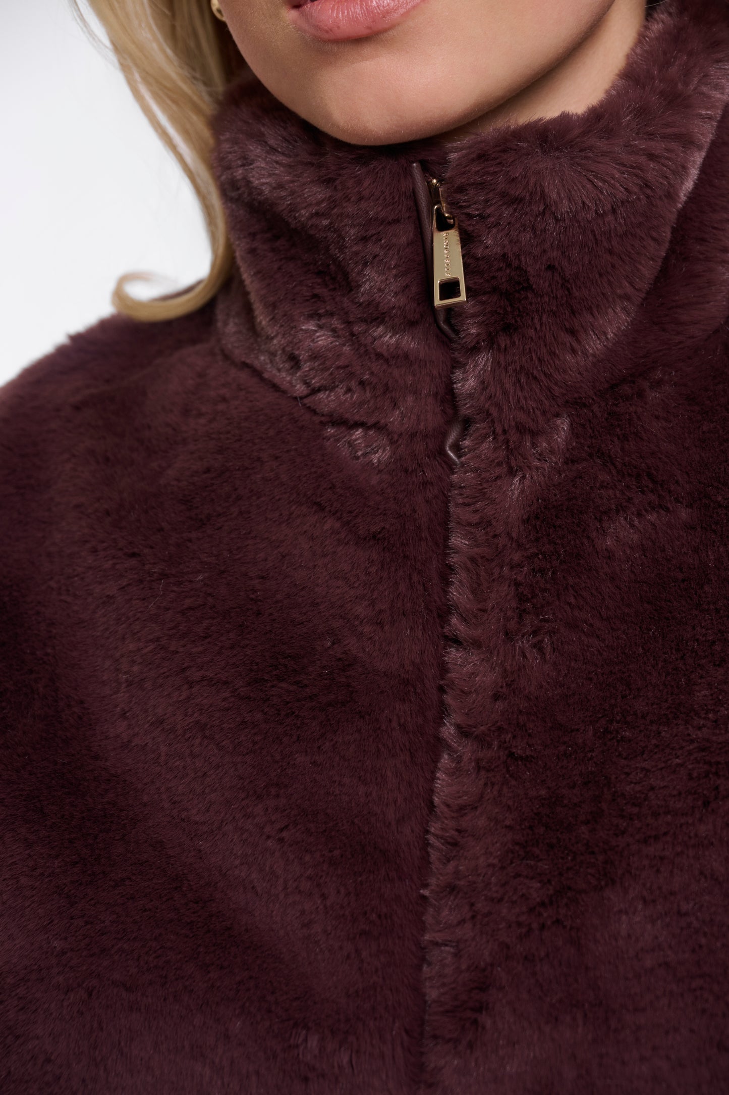 Close-up of a person wearing a dark brown fleece jacket with a zipper.