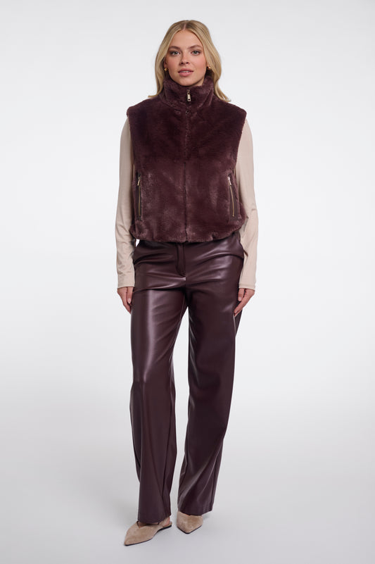 Woman wearing a brown leather vest and pants on a white background