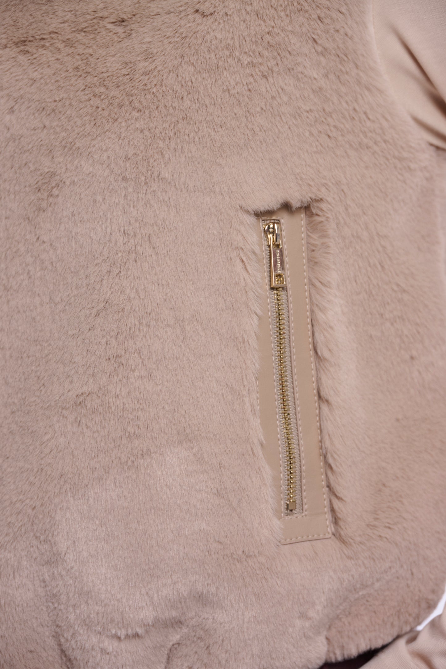 Close-up of a beige fleece jacket with a zipper pocket.