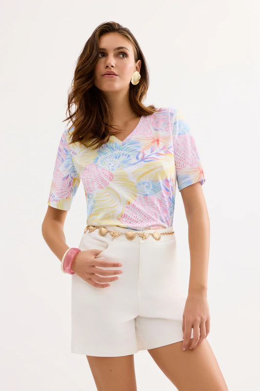 Woman wearing a colorful tie-dye top and white shorts on a white background