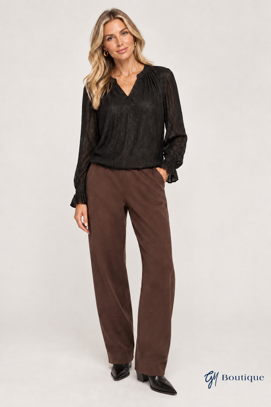 AI-generated styling mockup, not product photography: black Mos Mosh Ximena Glam blouse styled with brown MMARDIE Barrel Sweatpants, based on the store's product images. Trouser details may vary. Small GM Boutique logo at bottom right.