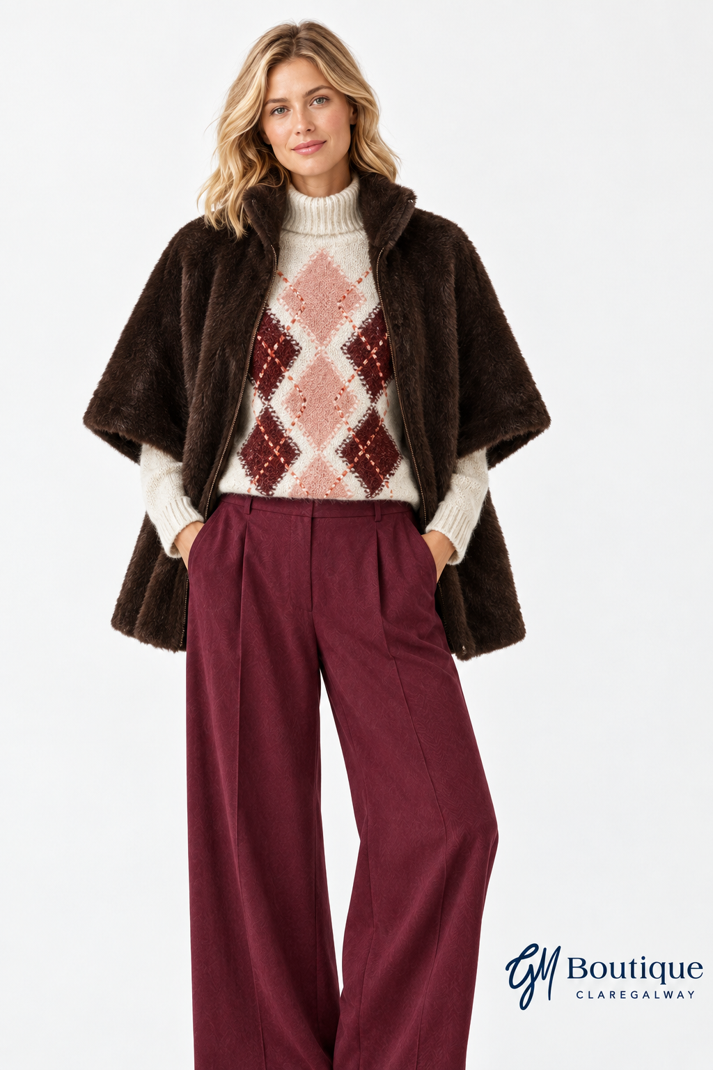 Model wearing the Micha faux fur cholcolate brown cape open with Oui argyle jumper and burgundy trousers with GM Boutique logo